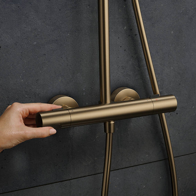 User operating the thermostat of the Hansgrohe Pulsify S Puro Shower Set, in Brushed Bronze, supplied by Deluxe Bathrooms.