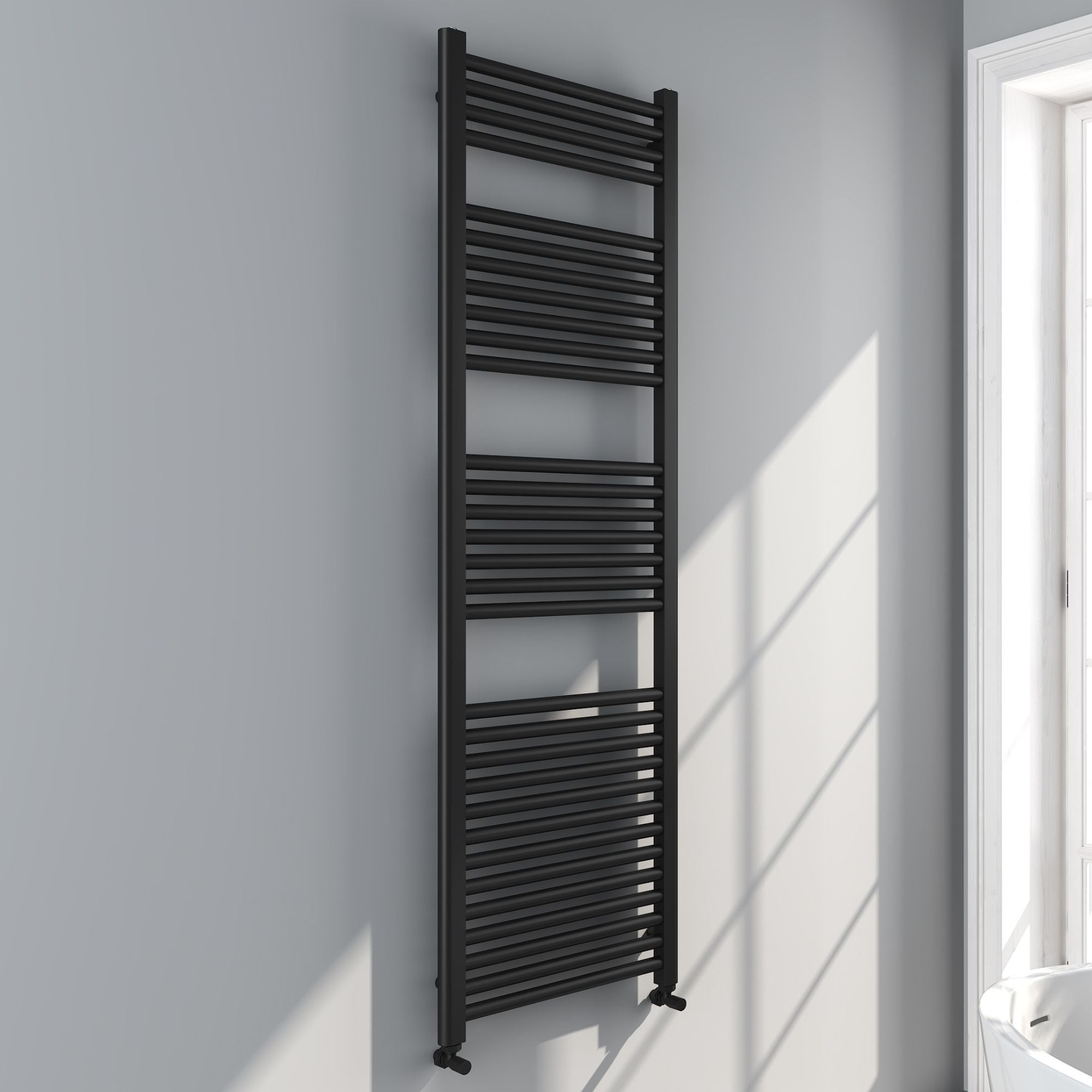 Soho matt black 1600x500mm towel radiator on a white wall with sunlight casting shadows deluxe bathrooms