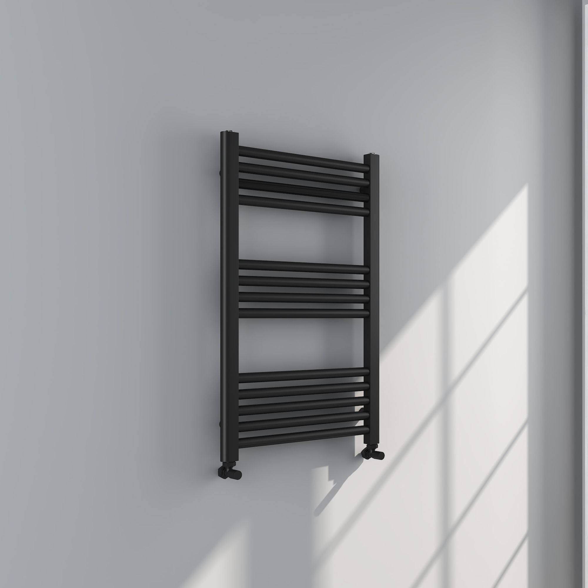 Soho matt black 800x500mm towel radiator on a white wall with sunlight casting shadows deluxe bathrooms